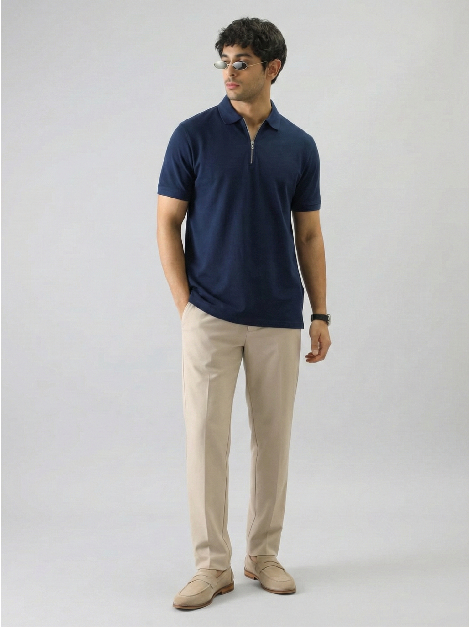 Man wearing a navy polo shirt and beige pants on a white background