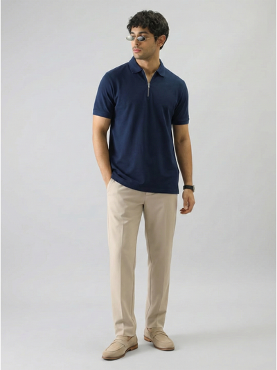 Man wearing a navy polo shirt and beige pants on a white background
