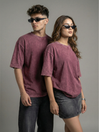 Two people wearing matching maroon t-shirts and sunglasses against a gray background